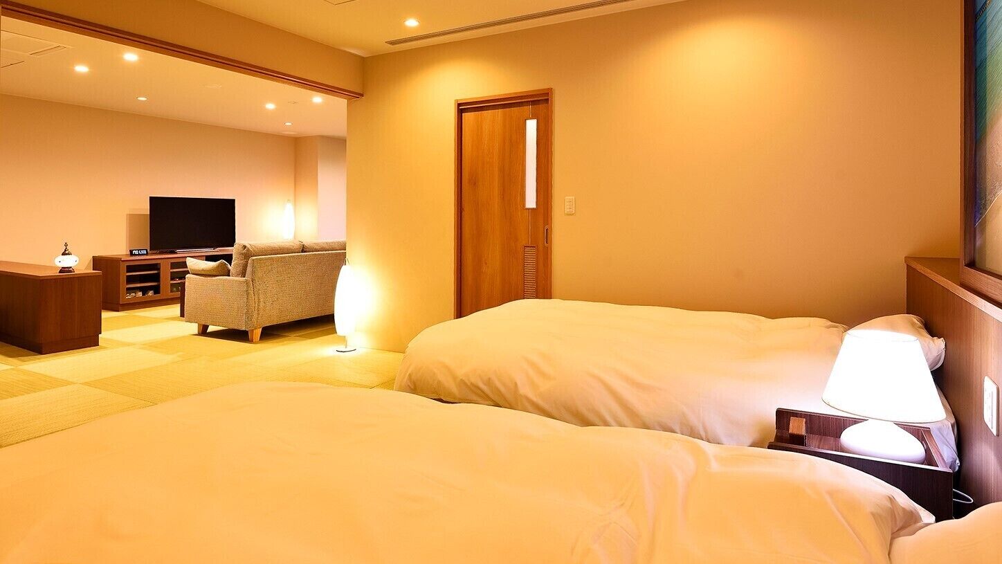 Una habitación de hotel con dos camas, televisión, escritorio y silla.