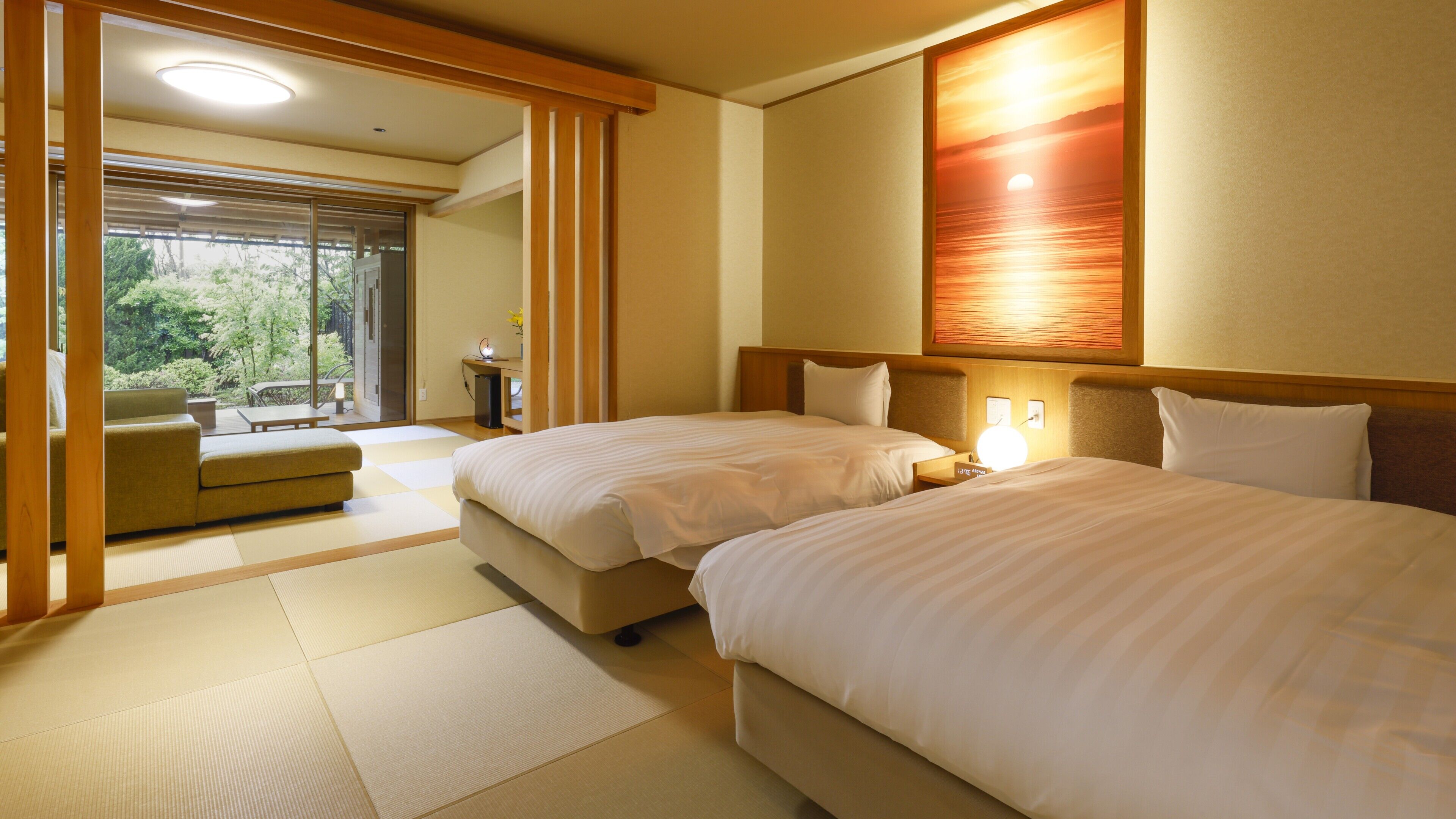 Habitación de hotel con dos camas, un sofá, un escritorio y vistas al exterior con vegetación.
