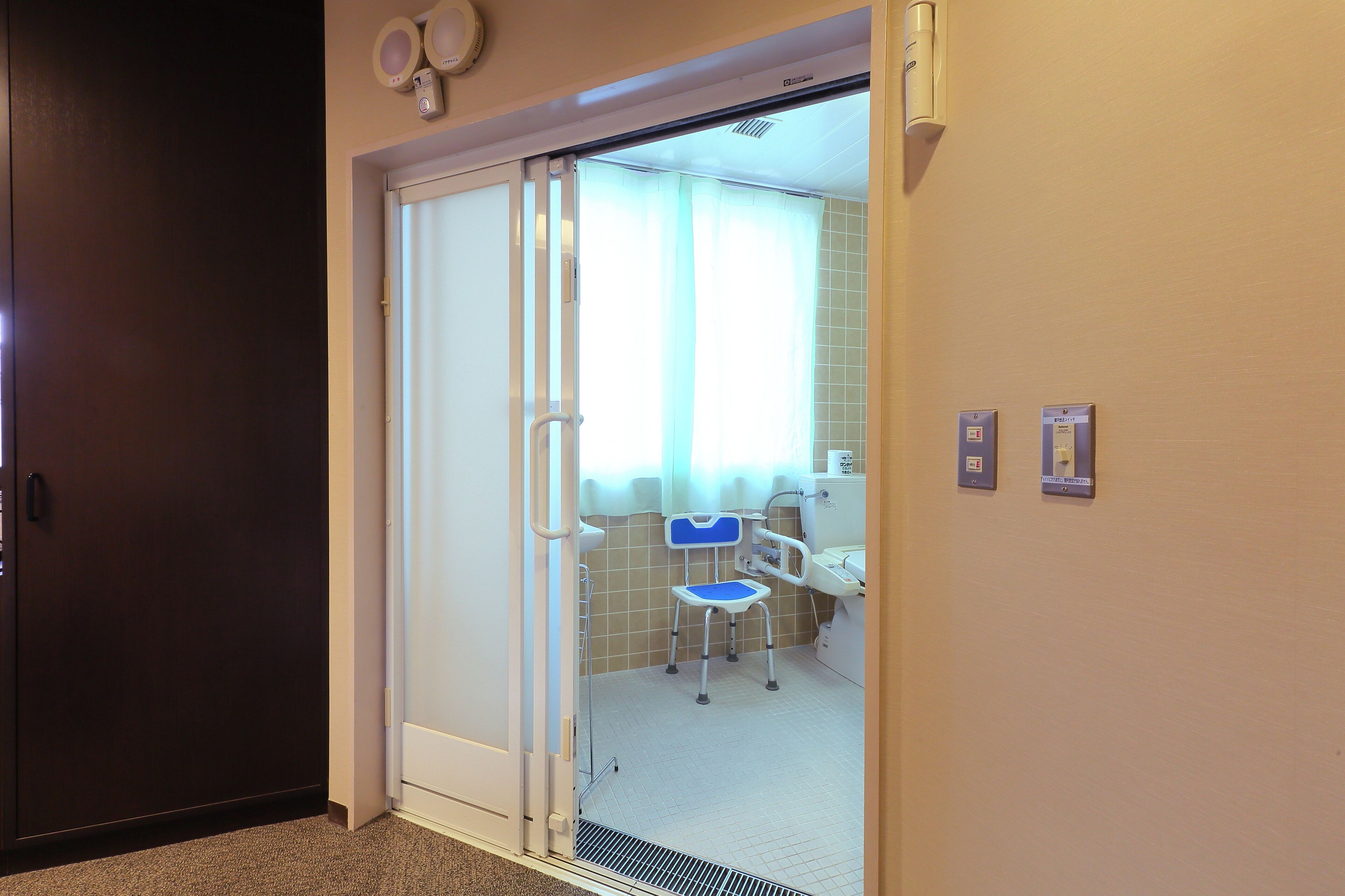 A hotel room with a sliding door leading to a bathroom that includes a sink, mirror, and toilet.