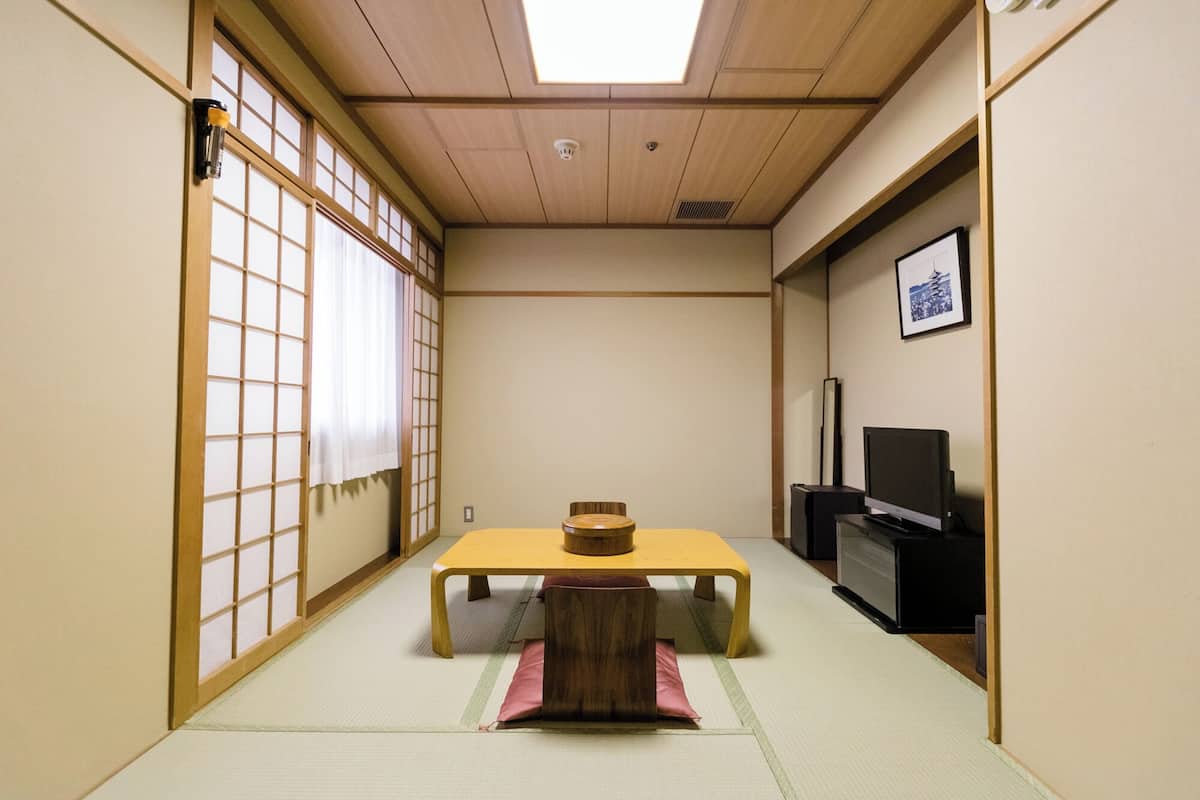 A traditional Japanese room with tatami flooring, a low table, a television, and a sliding door with shoji screens.