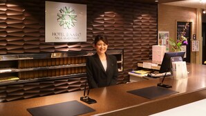 A reception desk at Hotel Binario SAGA ARASHIWA with a modern design, a digital screen, and a signboard.