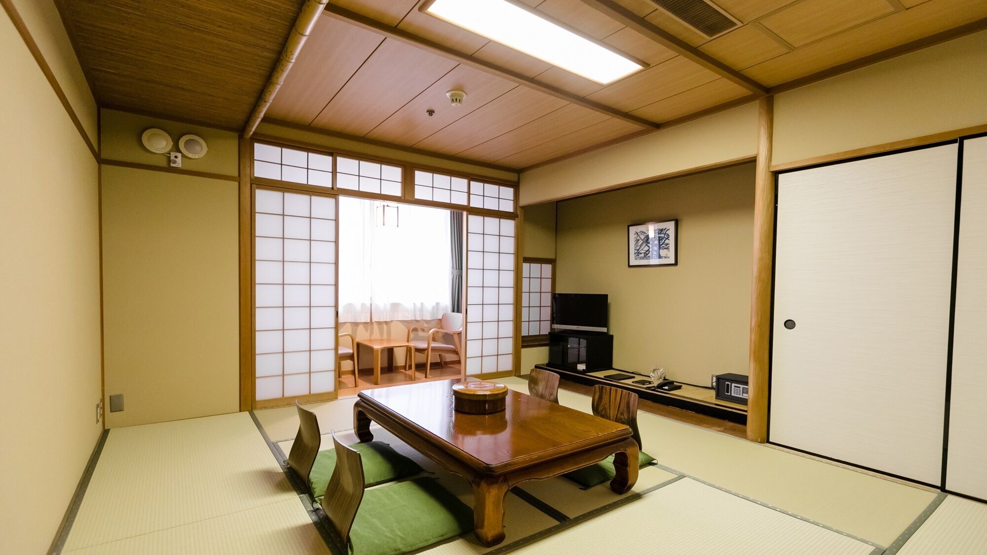 A traditional Japanese room with tatami flooring, a low wooden table, and a television.