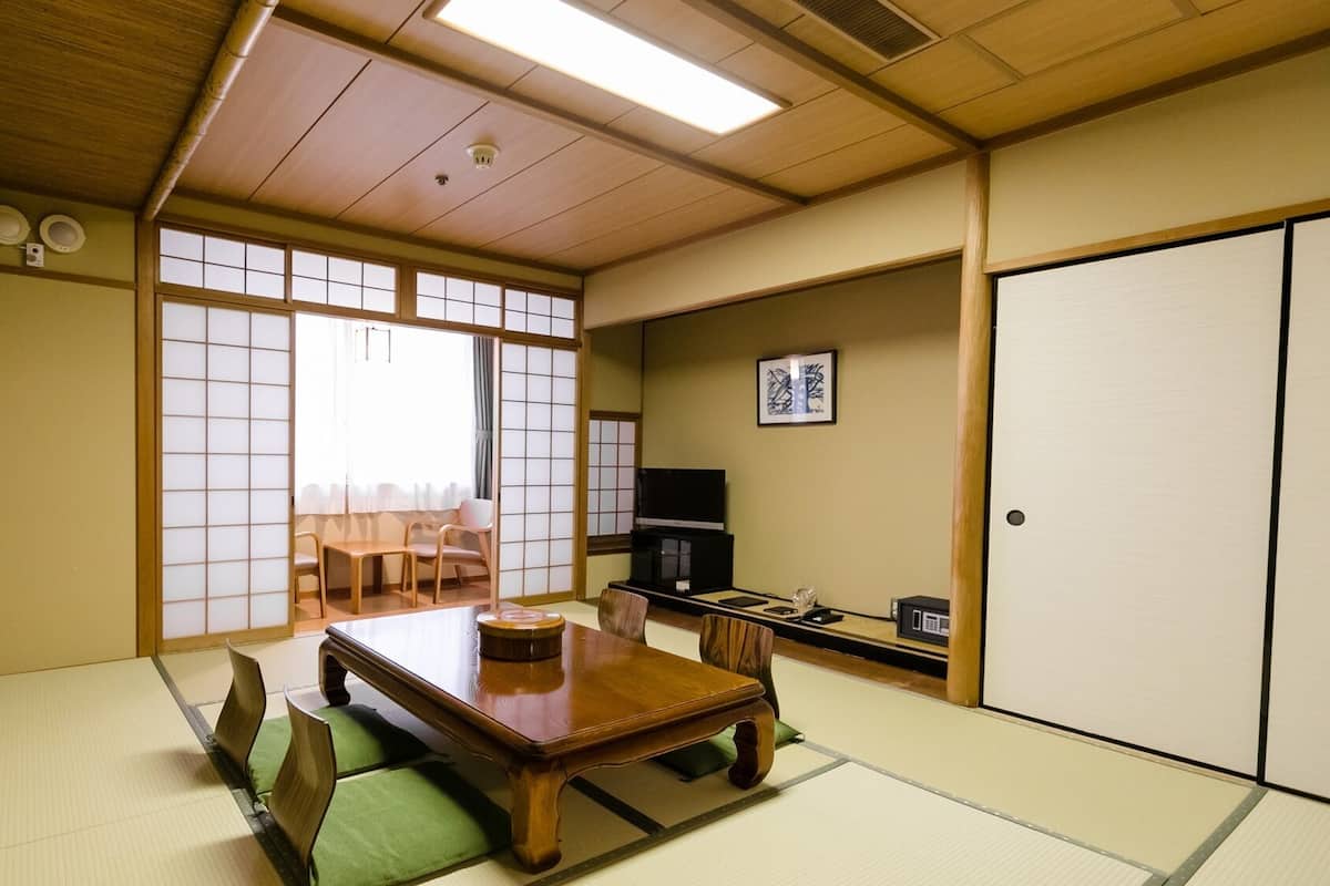 A traditional Japanese room with tatami flooring, a low wooden table, and a television.