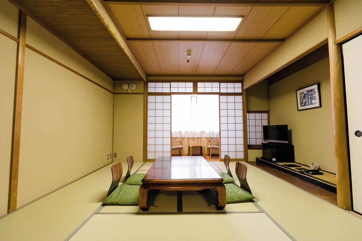 A traditional Japanese room with tatami flooring, a low wooden table, and sliding doors.