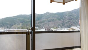 A view from a window overlooking a hillside with buildings and a mountain.