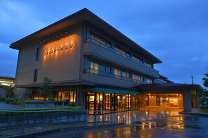 Un hotel moderno con una estructura de dos pisos, ventanas amplias y una entrada bien iluminada.