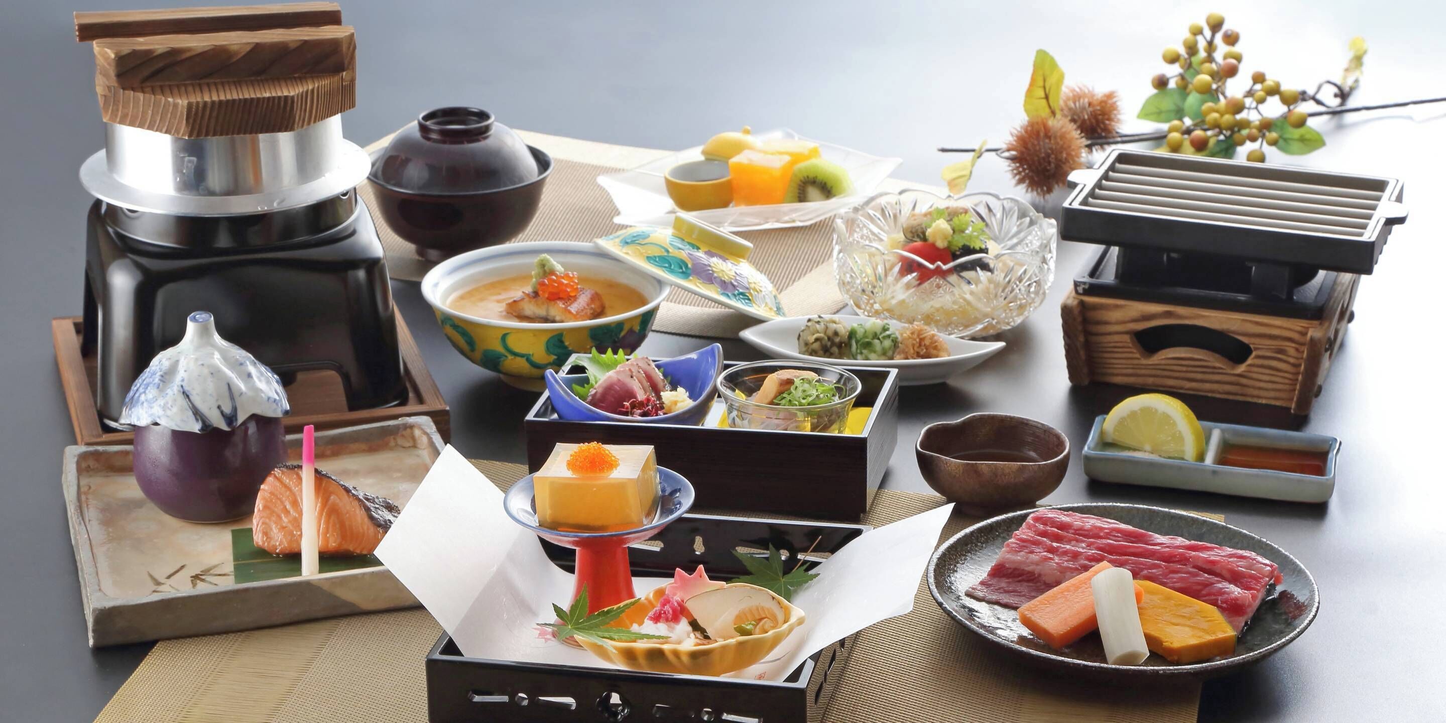 A variety of Japanese dishes and utensils on a table, including sushi, sashimi, and a teapot.