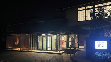 A building with a glass entrance, a sign with Japanese characters, and a small outdoor area with steps.