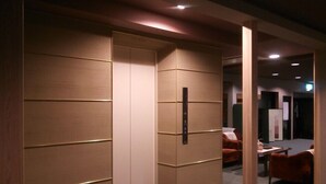 A modern hotel room with a sliding door partition, a small table, and a chair. - Kagetsu Ryokan (Maizuru)
