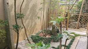 A traditional Japanese garden with stone pathways, bamboo fencing, and various plants. - Kagetsu Ryokan (Maizuru)
