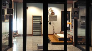 A hotel entrance with a reception desk, a waiting area with a sofa and a small table, and a sign indicating COVID-19 prevention measures. - Kagetsu Ryokan (Maizuru)