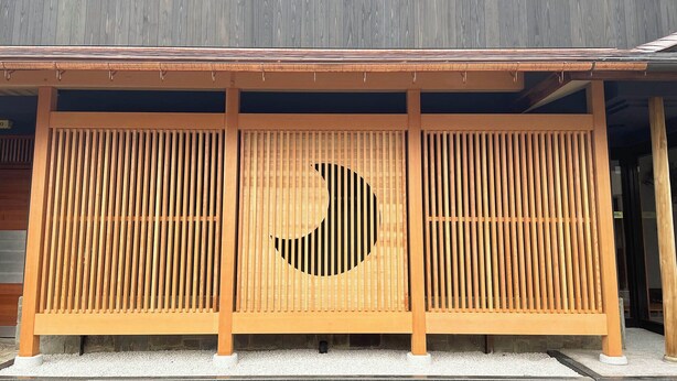 A traditional Japanese building with a wooden facade and a distinctive moon-shaped cutout. - Kagetsu Ryokan (Maizuru)
