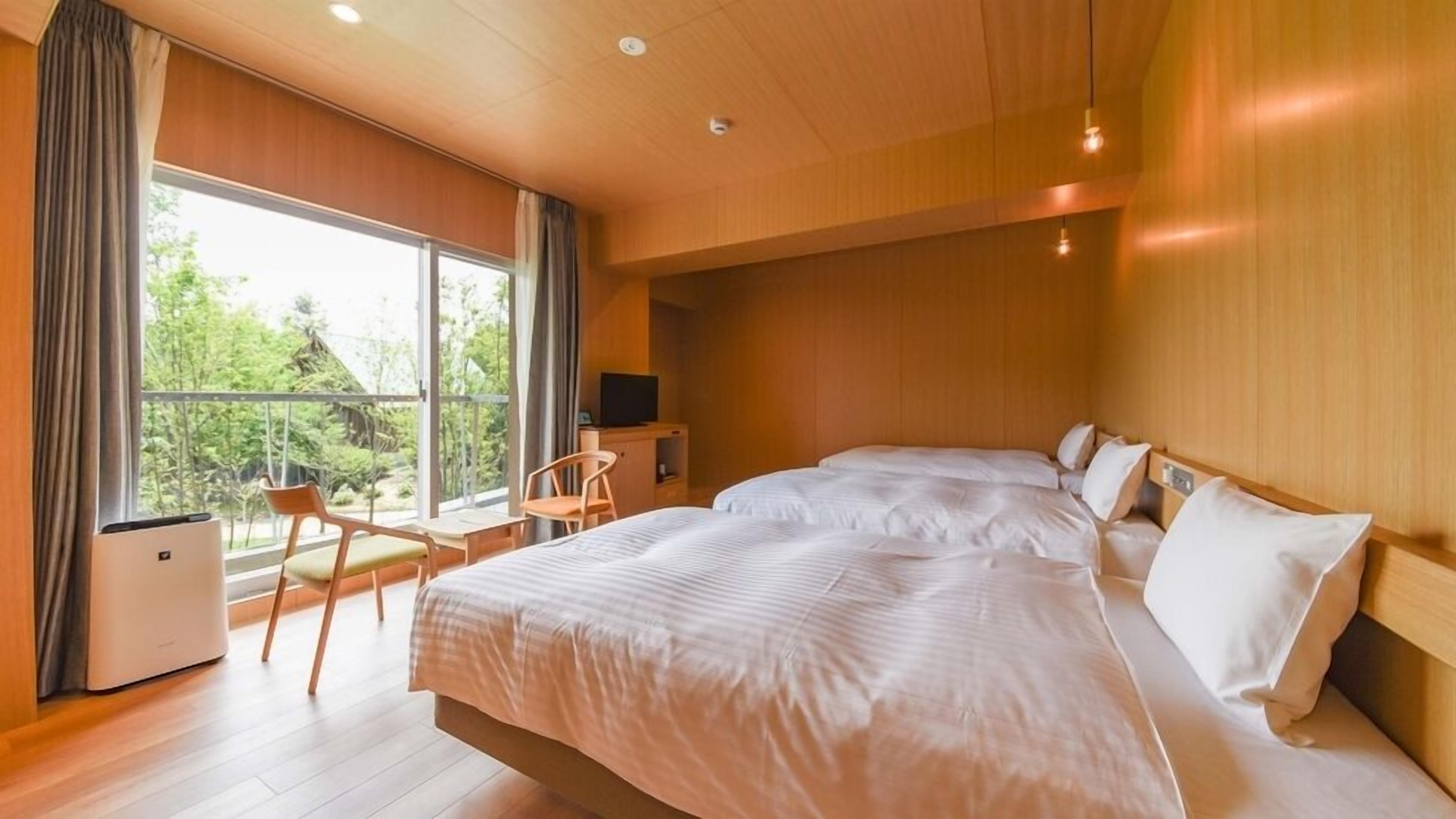 Quarto com duas camas, uma escrivaninha, uma cadeira, uma televisão e janela com vista para o verde.