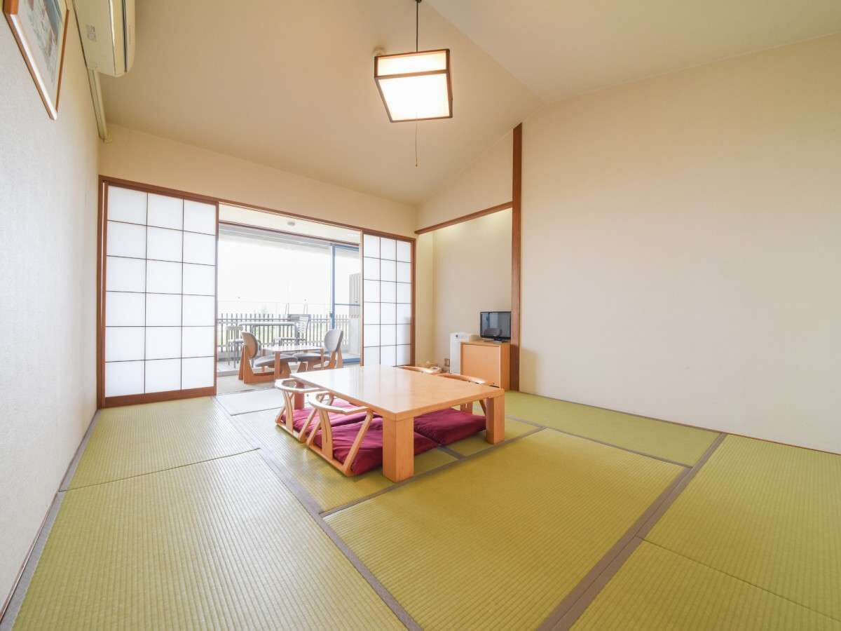 Een traditionele Japanse kamer met tatami vloerbedekking, een lage houten tafel en een schuifdeur naar een buitenbalkon.