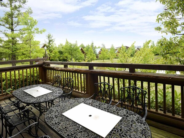 A wooden deck with outdoor seating, surrounded by greenery and trees. - Hotel The Day Osaka (Osaka)