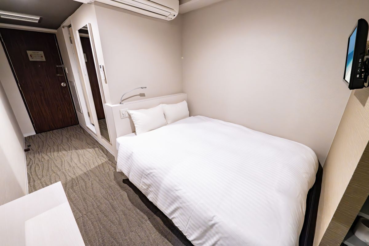 A hotel room with a bed, a desk, and a chair.
