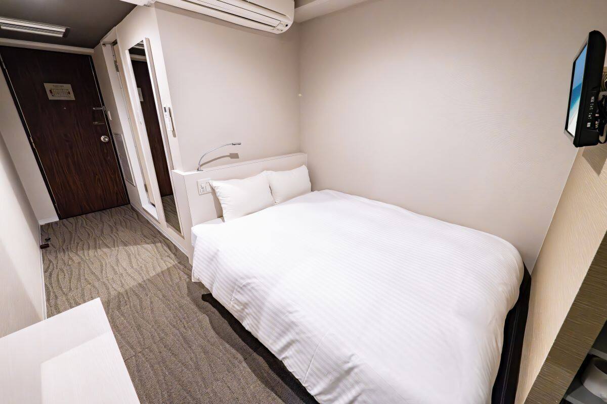 A hotel room with a bed, a desk, and a chair.
