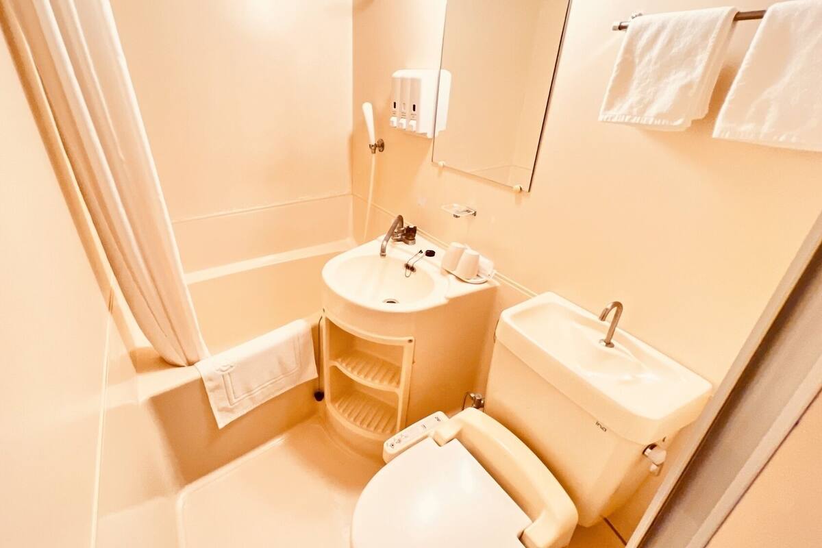 A bathroom with a toilet, sink, and shower area.