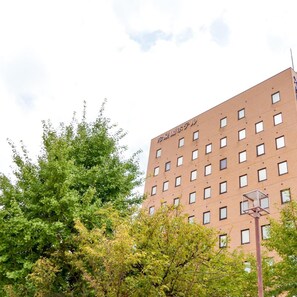 Un immeuble à plusieurs étages, doté d’une façade en briques, de nombreuses fenêtres et d’un panier de basketball visible au premier plan.
