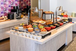 A buffet spread with various dishes and beverages, including bowls of food, plates, and cups, arranged on a marble counter. - JR WEST GROUP VIA INN UMEDA (Osaka)