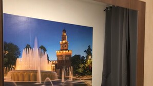 A hotel room with two beds, a large mirror reflecting a fountain and clock tower, and a dark curtain. - Albergo Corvetto corso Lodi (Milan)