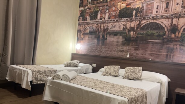 A hotel room with two beds, each with a patterned bedspread and pillows, a wooden floor, and a large wall mural of a bridge over water. - Albergo Corvetto corso Lodi (Milan)