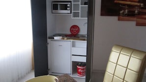 Eine kompakte Küchenzeile mit Mikrowelle, Kühlschrank und Coca-Cola-Kühler.