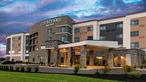 Un hotel Courtyard Marriott con un diseño moderno, que presenta fachada de piedra, varios pisos y una entrada cubierta.