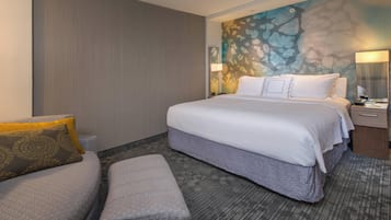 A hotel room with a large bed, a sofa, a carpeted floor, and a wall with a textured design.