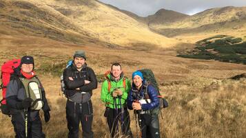 Three hikers in a mountainous area with dry grass and hills in the background.