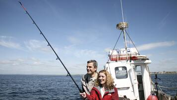 A boat on the water with two people holding fishing rods.