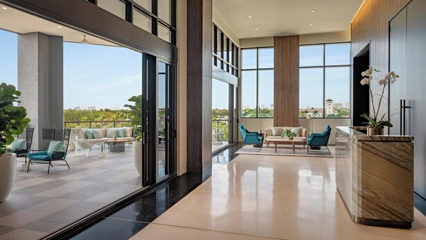 A spacious, modern interior with large windows, a marble reception desk, and a mix of seating areas. - The Dalmar, Fort Lauderdale, a Tribute Portfolio Hotel (Fort Lauderdale)