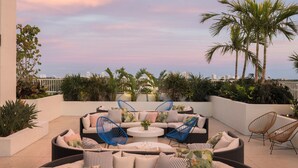 A rooftop patio with a curved sofa, blue chairs, and a round coffee table. - The Dalmar, Fort Lauderdale, a Tribute Portfolio Hotel (Fort Lauderdale)