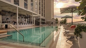 A rooftop pool with clear water, lounge chairs, umbrellas, and a bar area with a view of the city skyline. - The Dalmar, Fort Lauderdale, a Tribute Portfolio Hotel (Fort Lauderdale)