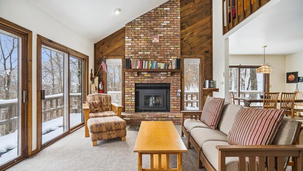 A cozy living room with a fireplace, wooden furniture, and a bookshelf. - Three bedroom Private home with Beautiful Views & Short Walk to the Home Stretch Trail! Frosty (Killington)