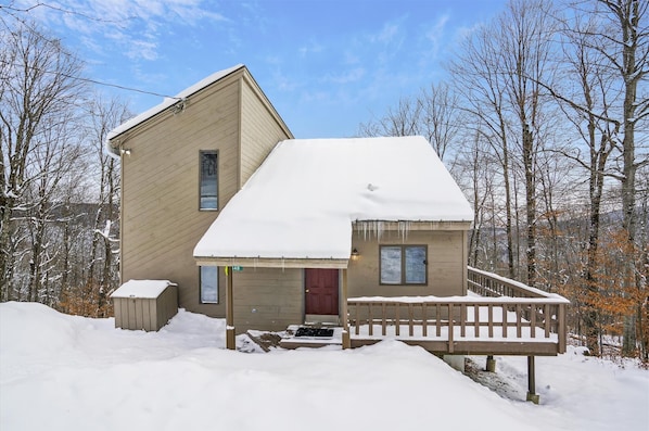 A two-story house with a snow-covered roof and a wooden porch. - Welcome to your ideal mountain escape! This delightful 3-bedroom plus loft (Killington)