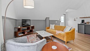Una sala de estar moderna con un sofá, una mesa de centro, un televisor y una estantería.