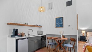 Cocina compacta equipada con lavavajillas, microondas y cafetera.  Cuenta con un comedor con mesa y sillas.