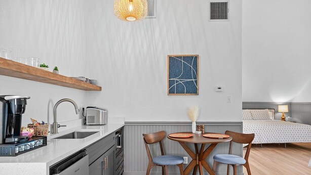 Una cocina compacta con electrodomésticos modernos, un comedor con una mesa redonda y sillas, y una cama en la habitación contigua.