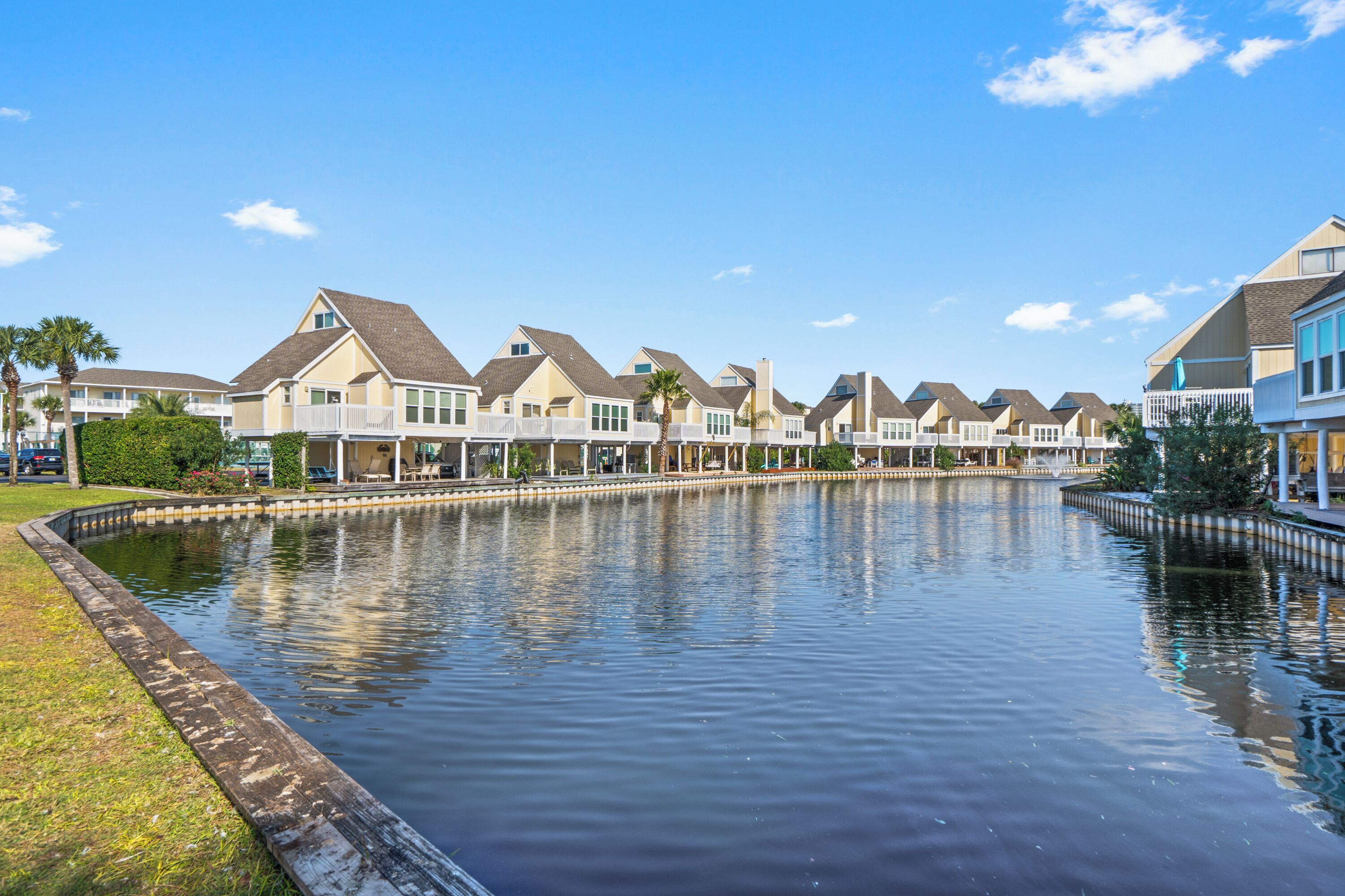 A waterfront property with multiple houses, a canal, and a grassy area.