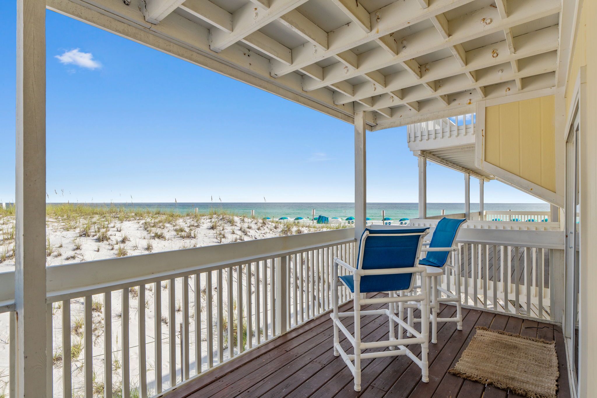 A wooden deck with a railing overlooking a beach.