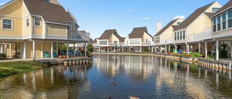 A row of waterfront houses with a pond in the foreground.