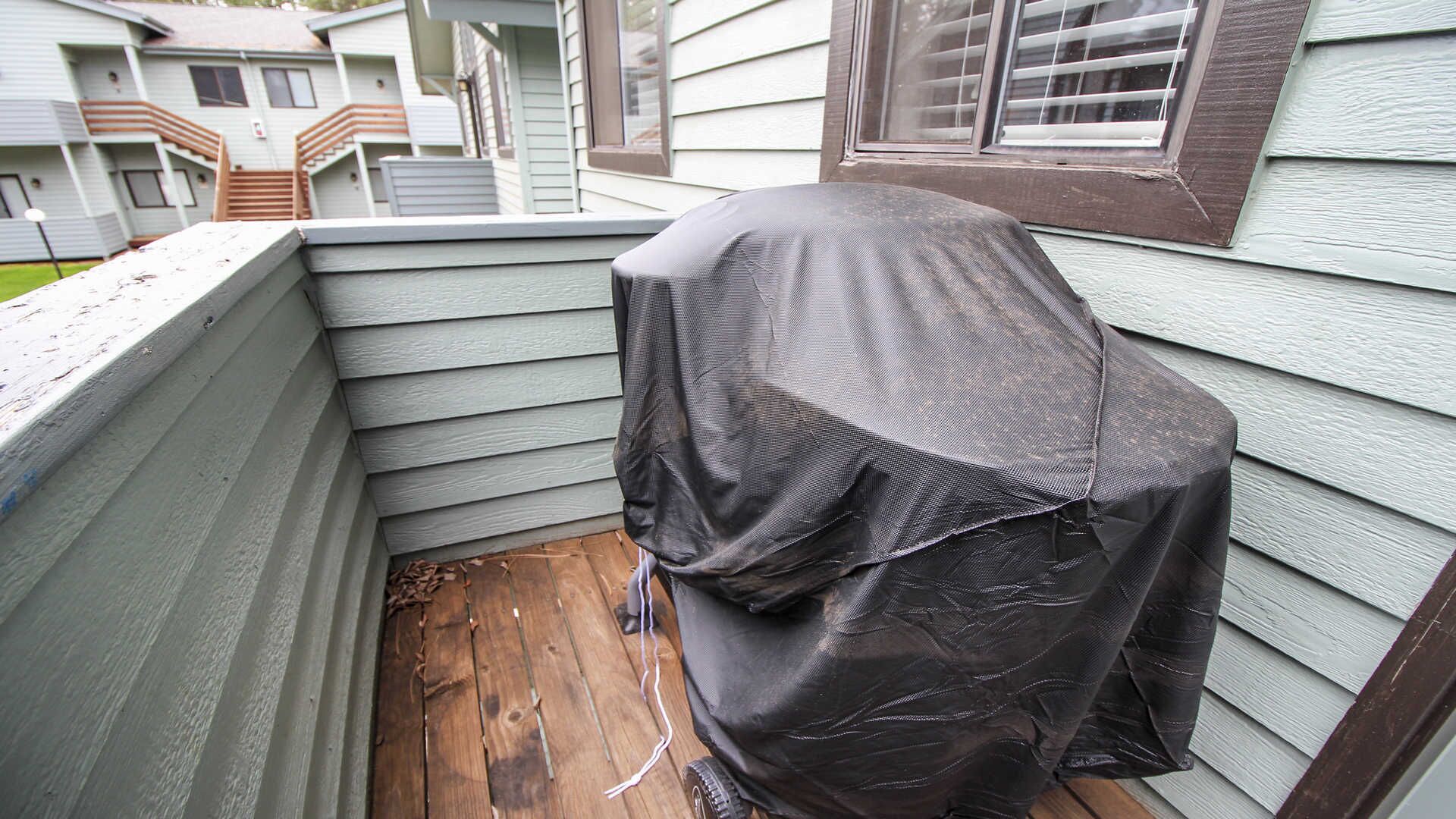 A corner of a building with a wooden deck and a covered object.