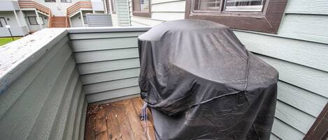A corner of a building with a wooden deck and a covered object.