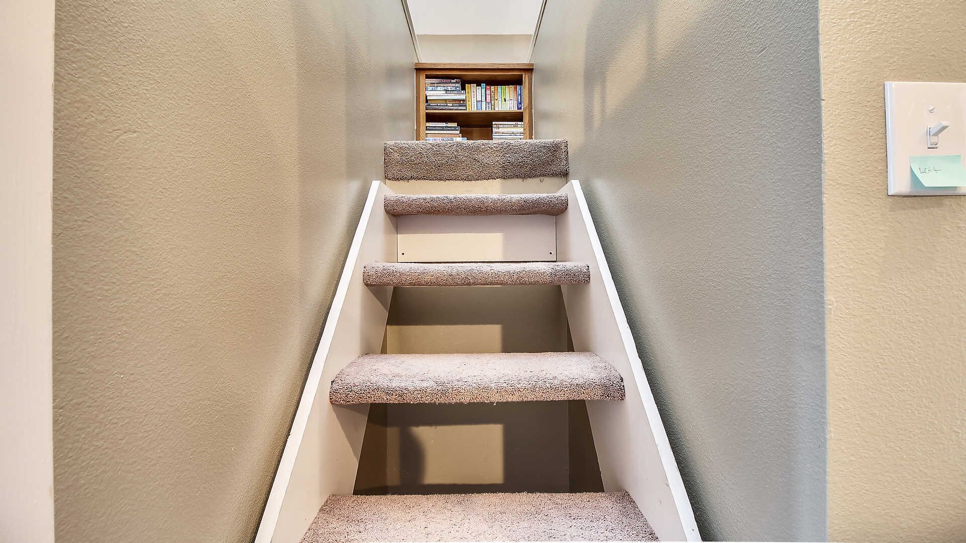 A carpeted staircase with a bookshelf at the top.