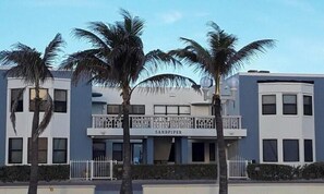 A building with a sign reading 'SANDPIPER' and a balcony with a railing.
