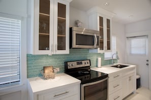 A modern kitchen with white cabinetry, a stainless steel microwave, a black stove, and a tiled backsplash. - Direct Ocean & Boardwalk Views - Beautifully Appointed Condo - Parking & Wi-Fi (Hollywood)
