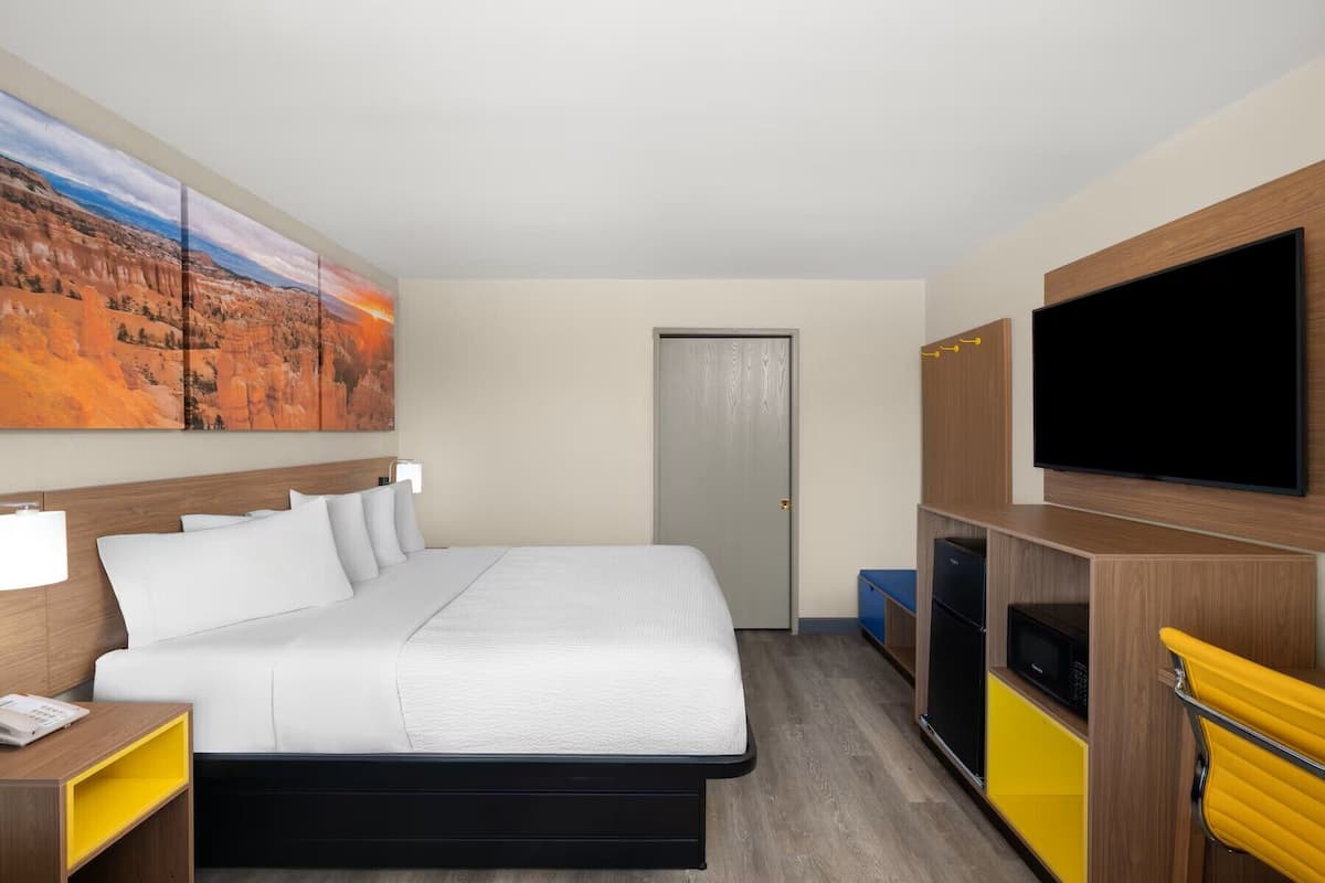 Ein Hotelzimmer mit Bett, Fernseher, Mikrowelle und einem Bild an der Wand.