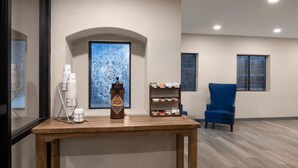 A room with a wooden table, a blue chair, a bookshelf, and a decorative wall piece. - Days Inn by Wyndham Safford, AZ (Safford)