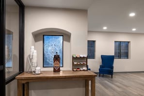 A room with a wooden table, a blue chair, a bookshelf, and a decorative wall piece.